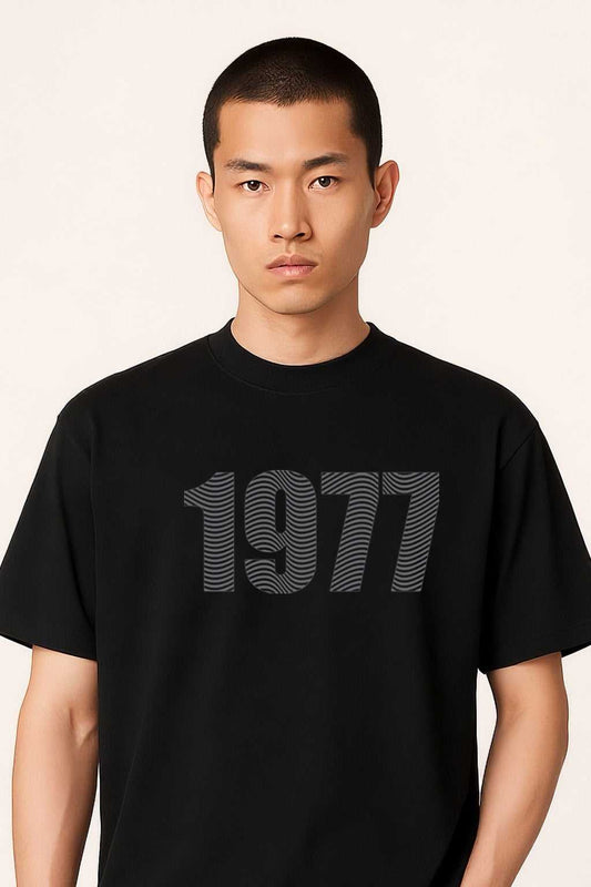 Close-up of 1977 Men's Oversize Streetwear T-Shirt showcasing the textured 3D '1977' graphic on the chest in a minimalist black design.