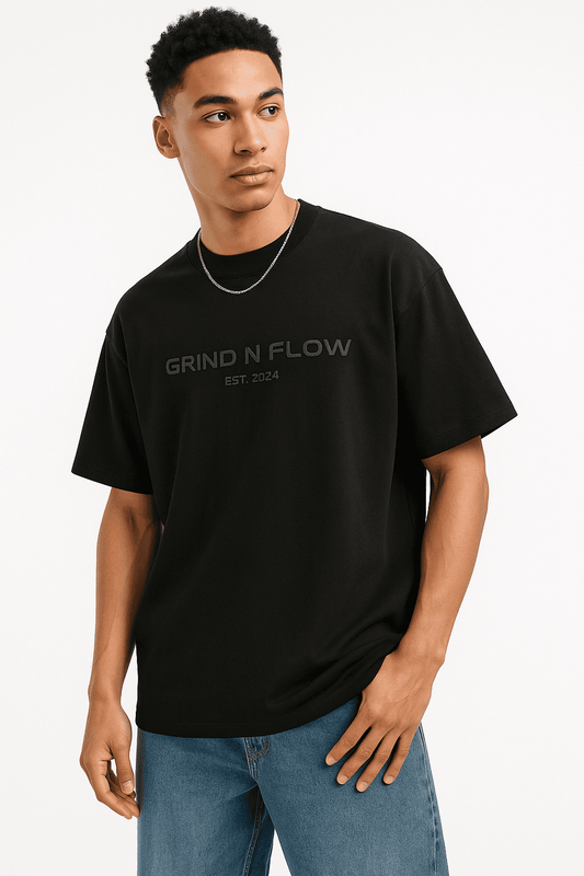 Grind n Flow Streetwear men's oversize streetwear t-shirt in black with 3D embossed 'GRIND N FLOW EST. 2024' graphic, styled with jeans.