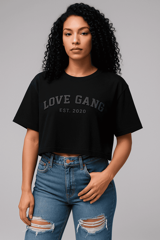 Love Gang Women’s crop top in black with bold front print, styled with ripped high-waisted jeans. Trendy tee for casual streetwear looks.