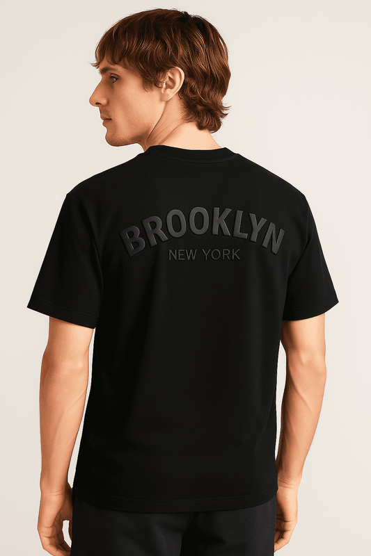 Men's oversize t-shirt in black with bold 3D 'BROOKLYN NEW YORK' text on the back. Made from organic cotton for streetwear style and comfort.