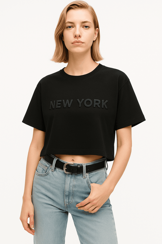 New York Crop Top - Women's NYC Crop Tee in black with bold lettering, soft cotton fabric and relaxed fit, styled with high-waisted jeans.