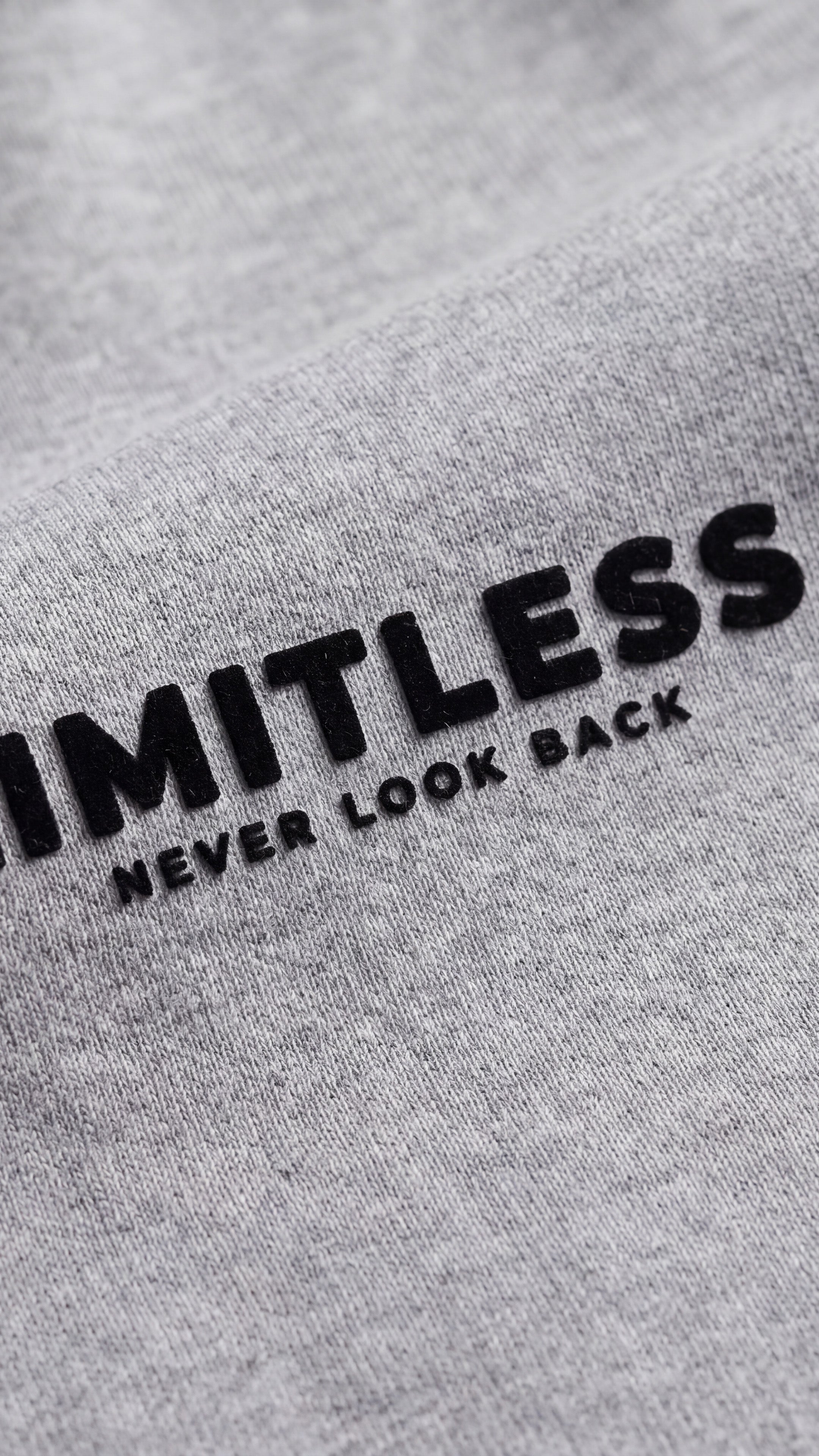LIMITLESS Fleece Hoodie (Heather Grey) - close-up of raised black flock LIMITLESS / NEVER LOOK BACK print on heavyweight fleece - Grind n Flow