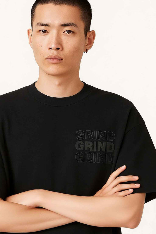 Grind Men's Streetwear T-Shirt with arms crossed, emphasizing the premium 3D embossed design and minimalist oversized streetwear look.