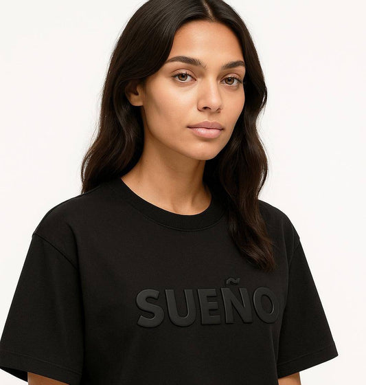 Close-up of Sueno - Dream Spanish Tee with raised 'SUEÑO' lettering. Stylish Latina pride t-shirt in soft black cotton.