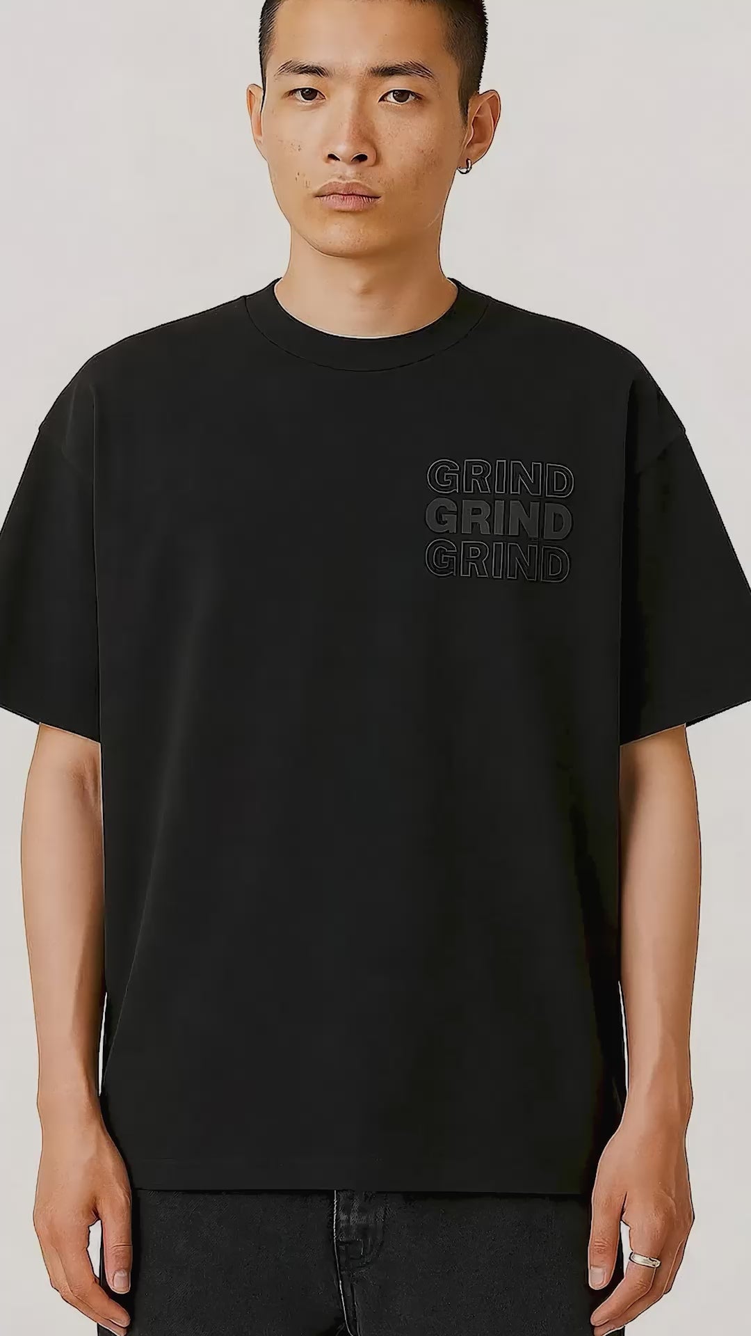 Grind Men's Streetwear T-Shirt in black with 3D embossed chest detail, styled in a relaxed oversized silhouette for modern streetwear.